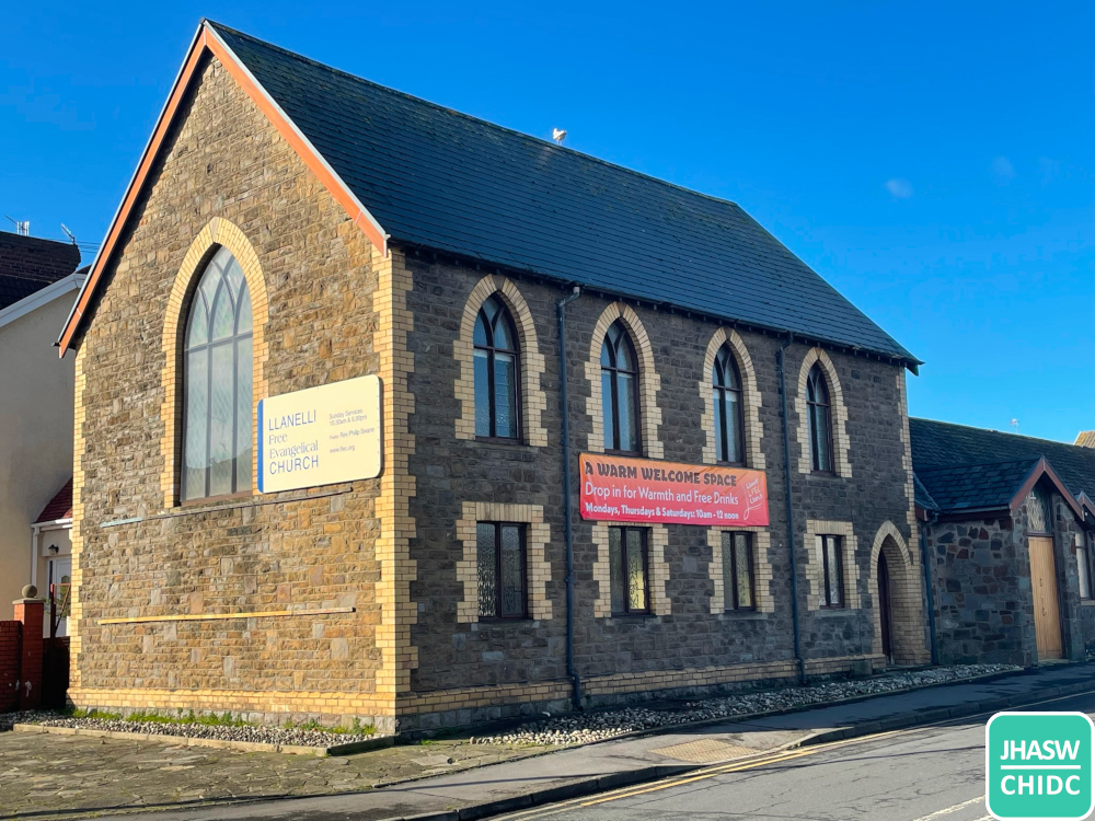 A photograph of the Llanelli synagogue building today as a two-storey church with large arched window at end and two rows of four smaller arched windows on the side, and a door.